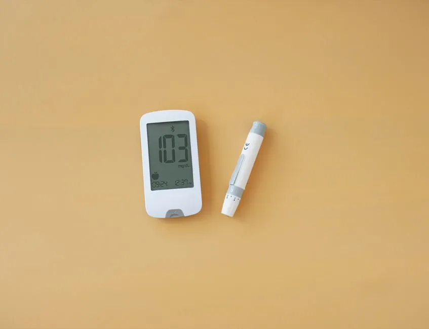 Close-up of a blood glucose meter and lancet pen on a flat surface, indicating health monitoring.
