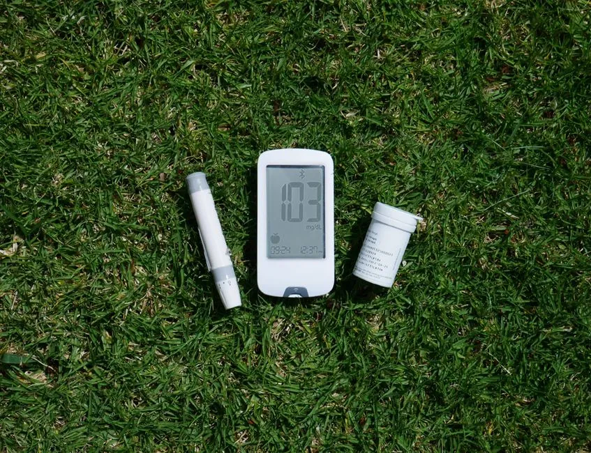 Diabetes management tools including glucose meter and test strips on grass, highlighting outdoor use.