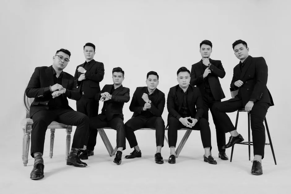 Stylish black and white portrait of seven men posing in suits, demonstrating elegance and fashion.