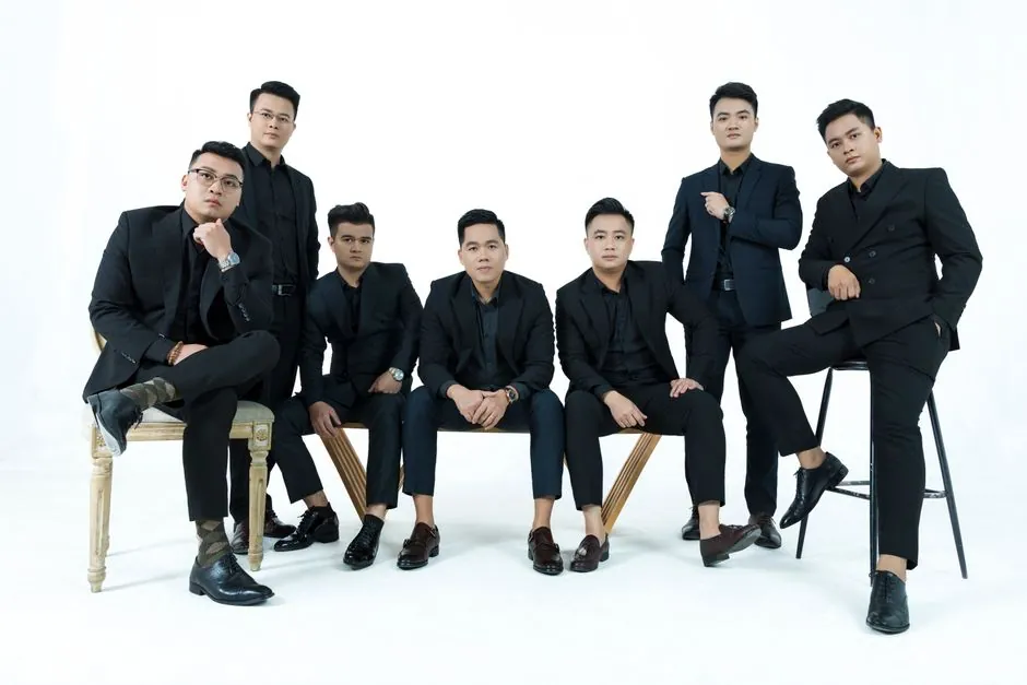 A stylish group of men in suits posing elegantly against a white backdrop in a studio setting.