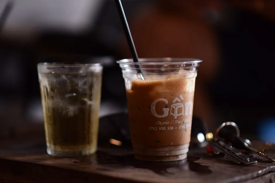 Close-up of iced coffee and cold brew beside keys, capturing a casual cafe vibe.