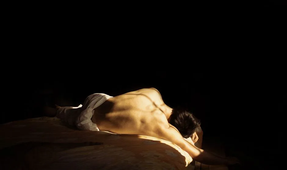 A dramatic and artistic portrayal of a nude person with striking shadows.